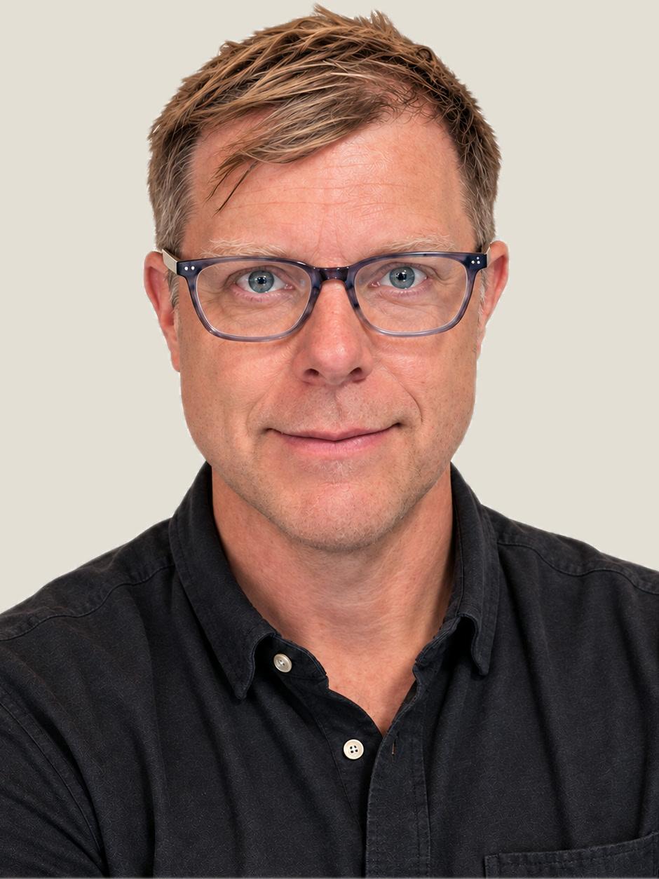 Kody Kochaver in a dark button-down shirt and glasses.
