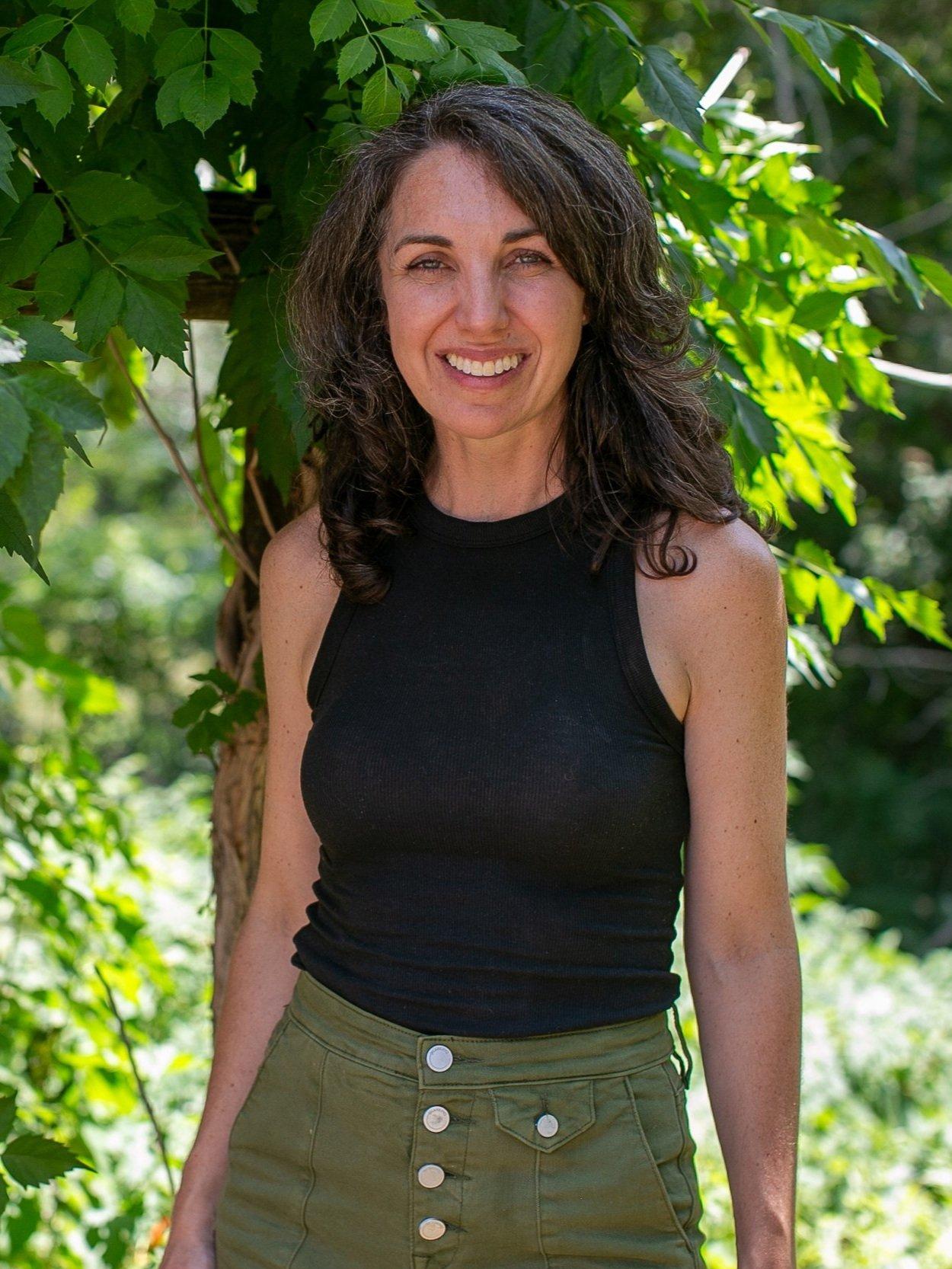 Leah Kochaver of Middle West Studio, outdoors among green foliage