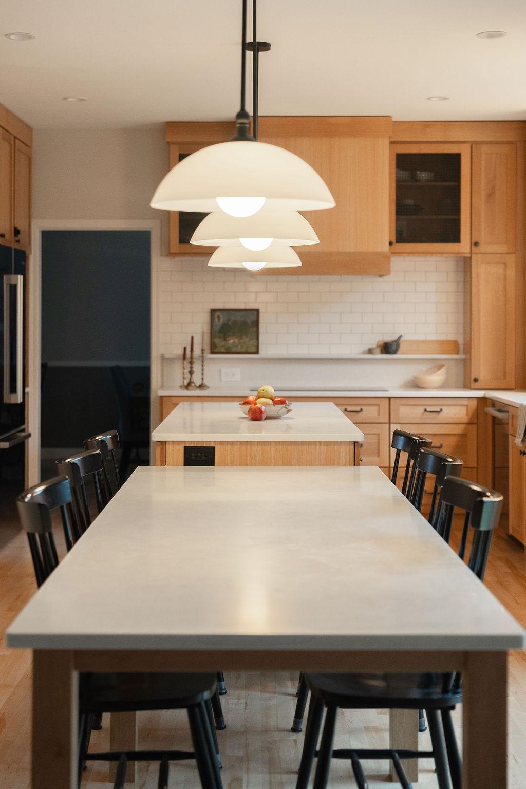Sahara Circle kitchen by Middle West Studio, with warm timber cabinetry, a dining table, and pendant lights
